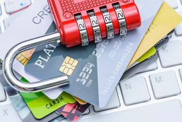 Cybersecurity, online fraud prevention, personal data encryption and protection, credit card security : Several credit cards with a red combination padlock placed over a computer keyboard.