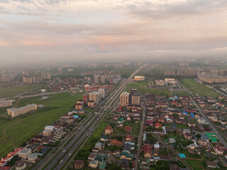 Drone view of the town and mountains at sunset. Beautiful clouds covered the city. Bright evening...