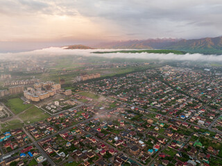 Drone view of the town and mountains at sunset. Beautiful clouds covered the city. Bright evening...