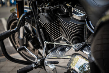 Fototapeta premium A motorcycle engine is shown in detail, with the black and silver parts reflecting the sunlight. Concept of power and strength, as well as the sleek design of the motorcycle