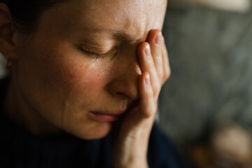 Sad woman 30-35 year old with tears on her face and closed eyes in dark room. Depression.