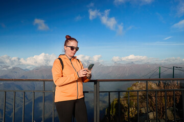 a woman travels in the mountains and plots a route on the navigator in her smartphone