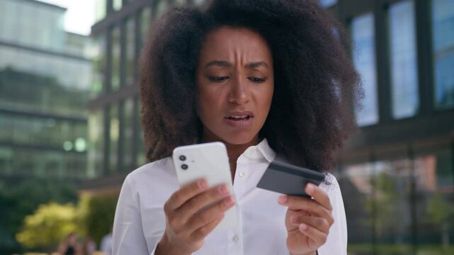 Sad upset African American woman girl businesswoman business user mobile phone smartphone bank card credit pay virtual finance debt problem error loss salary money failure female employee outside city