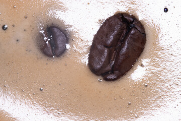 Coffee beans floating in a morning cup of hot coffee.