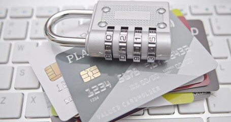Cybersecurity, online fraud prevention, personal data encryption and protection, credit card security : Several credit cards with a silver combination padlock placed over a computer keyboard.