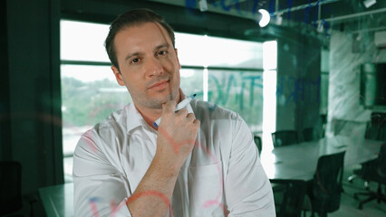 Smart businessman thinking about start up project in front of glass board. Smiling male project...