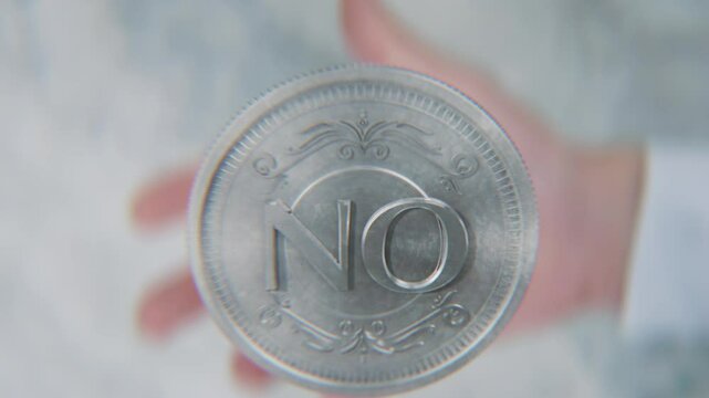 A hand flips a coin marked Yes and No, spinning toward the camera in slow motion