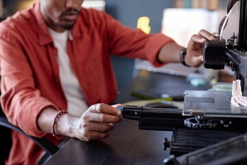 Person operating advanced 3D printer in a modern workspace, focusing on the machine's settings. Detailed components and environment visible in the background