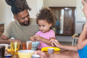 Black father and mixed race daughter having breakfast together, authentic family moment
