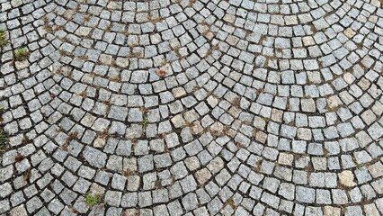 Horizontal photo of old paving slabs, a cobblestone pavement texture. Perfect as a background or texture, it illustrates travel and strolls in historic European cities known for their charming tiles