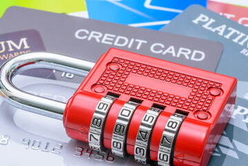 Obraz premium Financial or credit card security, identity theft prevention, and data protection : A red combination padlock placed over multiple credit cards, depicting themes of cybersecurity, fraud protection.