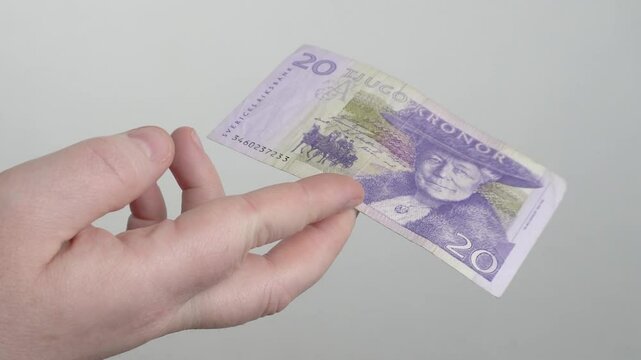 Women's hands with an old-style 20 Swedish kronor bill. They are trying to pay for the purchase