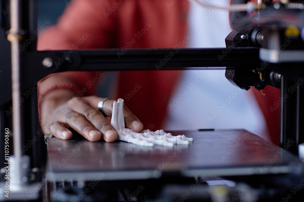 Poster close-up of a person operating 3d printer with detailed view of hand and printed object. red sweater
