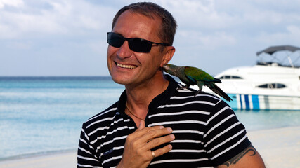 Photo shoot of a young man on the beach with a parrot. 
