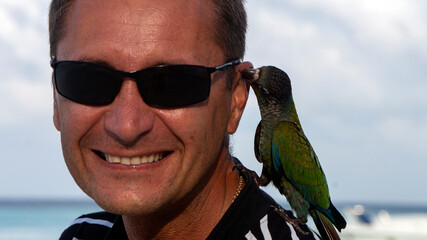 Photo shoot of a young man on the beach with a parrot. 