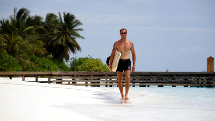 Young guy with a surfboard on the beach