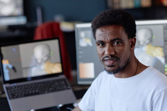 Portrait of African American man standing near computer screen in office environment managing digital work and projects showcasing his professional dedication and workplace surroundings
