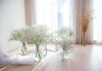 white room with vases and white flowers gypsophila window and curtains