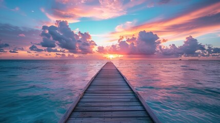 Obraz premium A serene wooden pier extends into a vibrant sunset over calm ocean waters.