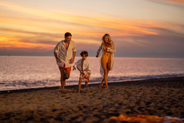 A happy family enjoying their holiday at sunset, laughing and having fun together by the beach.