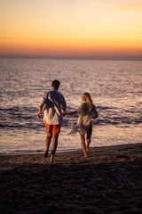 Fototapeta premium A happy couple sharing romantic moments at the beach during sunset, with the golden hues of the setting sun creating a serene and intimate atmosphere.