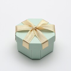 Obraz premium A small, light blue hexagonal gift box adorned with a golden ribbon sits on a plain background, symbolizing celebration and surprise, isolated on white background for di-cut