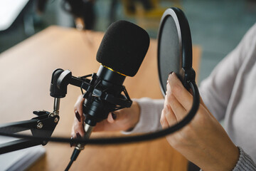 Podcast microphone set up with pop filter on wooden desk at home studio