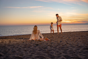 A happy family enjoying time together at the beach during sunset, playing and having fun.