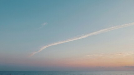 Fototapeta premium Sky transitions to dusk over calm ocean water as soft clouds linger at sunset near the horizon