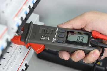 Measurement of electrical parameters in a switchboard using a multimeter.