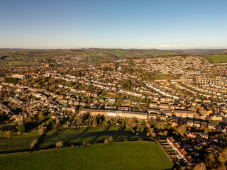 Obraz premium British suburban residential houses covering rolling green hills at sunset, aerial view