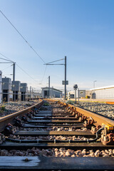 Railway tracks converging into the distance under a clear blue sky