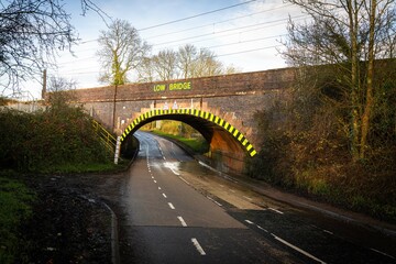 Low bridge sign and black and yellow hazard stripes under railway bridge