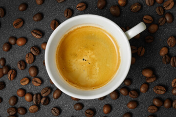 top view of espresso with crema in cup and coffee beans near on black table