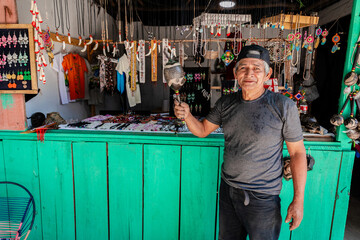 Peruvian jungle artisan working on his products to sell them in his market stall.