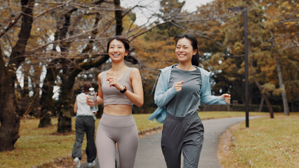 Fototapeta premium Women, running and bonding for fitness, cardio and training for body goals, wellness or active in morning. Outdoor, smile and workout for Japanese friends, health and together for exercise routine