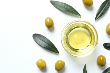 Bowl of fresh olive oil and olives with leaves on white background