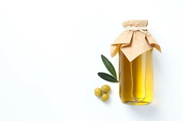 Bottle of fresh olive oil and olives with leaves on white background