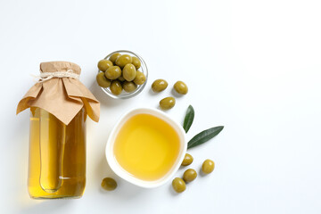 Bottle of fresh olive oil and olives with leaves on white background