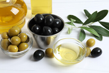 Bowl of fresh olive oil and olives with leaves on the table 