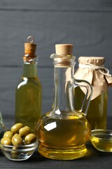 Bottles of fresh olive oil and olives on table