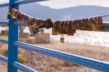 A blue fence with a chain and a row of locks hanging from it