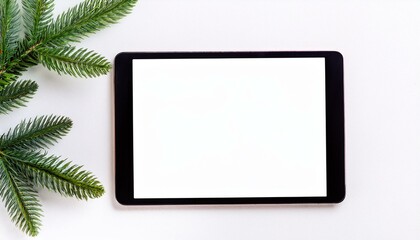 A black tablet with blank copy text screen and Christmas tree branches on white background	