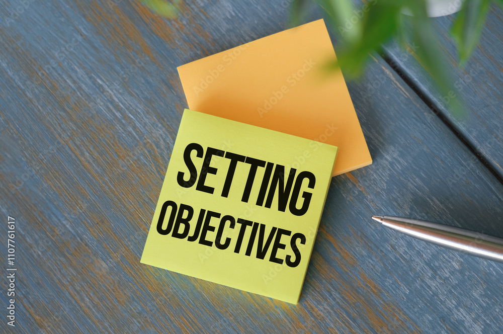 Poster setting objectives text on clipboard on wooden background