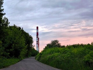 The pipes of the power plant on a country forest road. Evening.