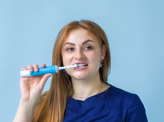 A young woman is brushing her teeth with an electric brush. snow-white teeth. proper dental care