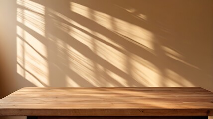 A empty wooden tabletop against a beige wall with a background of sunshine shadows