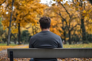 Fototapeta premium A person sitting alone on a park bench, surrounded by nature