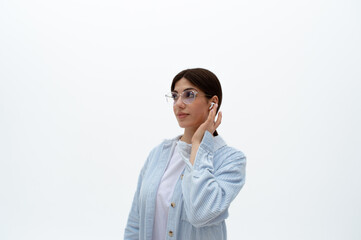 Cheerful young eastern woman in a blue shirt with headphones, keeping her hands on it, enjoying...