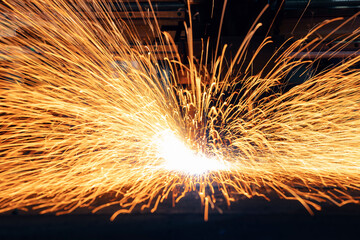 Plasma CNC plasma cutter machine cuts metal material with sparks, industrial background